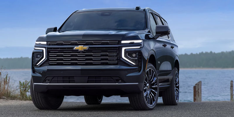 2025 Chevrolet Tahoe SUV parked near a lakeside with modern front grille and LED lighting
