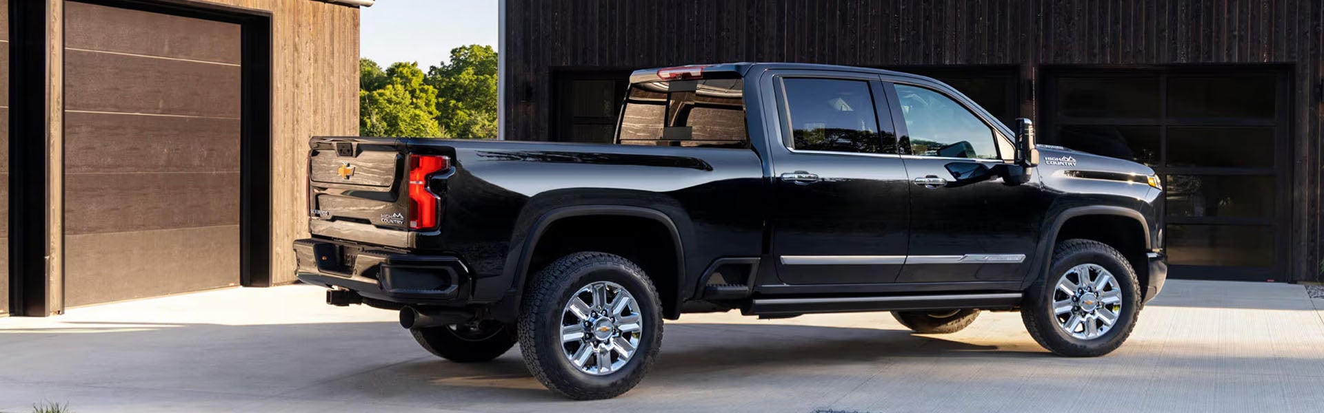 Black 2026 Chevrolet Silverado 2500HD rear-side view with long bed and chrome wheels.