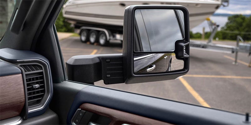 Chevrolet Silverado side mirror showing trailer in reflection.