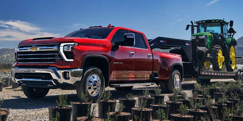 Red Chevrolet Silverado truck towing a trailer in an outdoor setting.