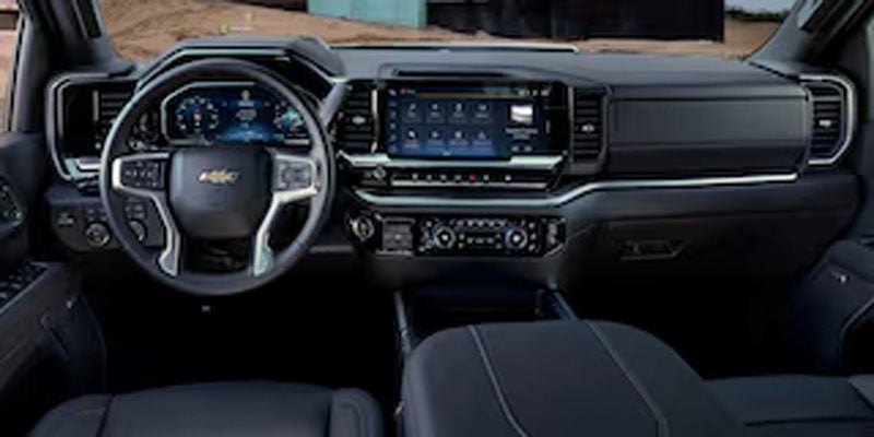 Interior of Chevrolet Silverado showing steering wheel, dashboard, and touchscreen display.