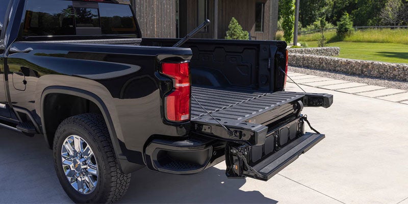 Black Chevrolet Silverado truck with tailgate open showing cargo bed.