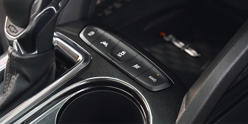 Close-up of SUV center console with drive mode buttons and cup holder.