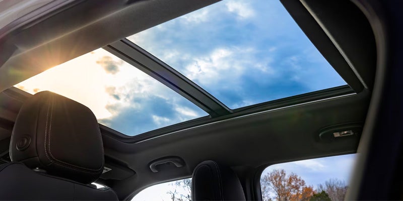 SUV interior with panoramic sunroof showing sky.