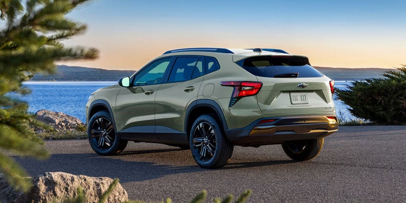 2026 Chevrolet Trax in green parked by the coast, showcasing its sleek rear design.