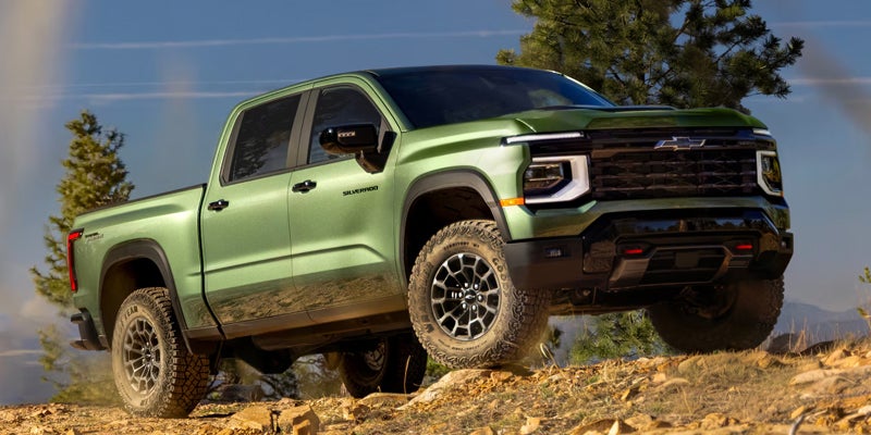 Green Chevrolet Silverado truck driving over rocky terrain.